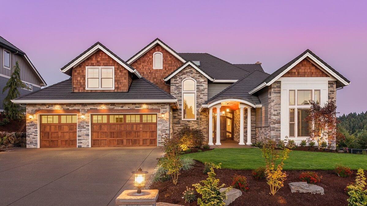 Front view of a luxury home with a purple sunset in the background.