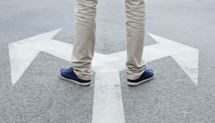 Man standing on arrows painted on asphalt.